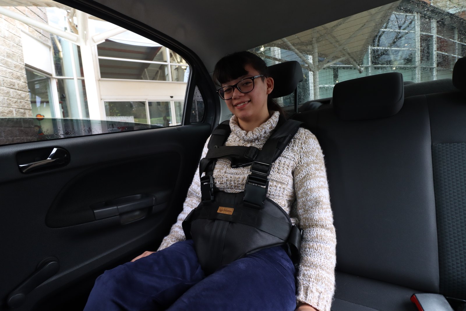 Persona usando el cinturón Ancora en el asiento trasero de un auto